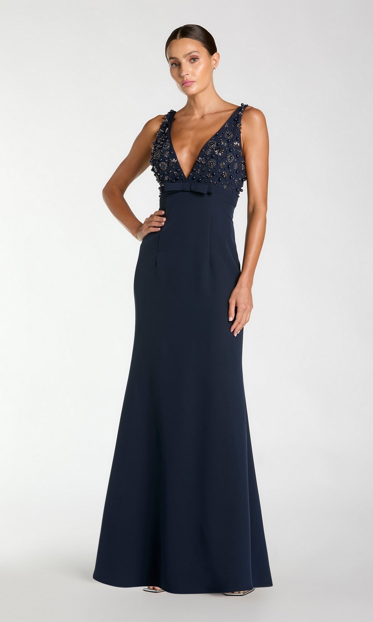 Woman models the Mac Duggal 2278 Beaded-Bodice Long Prom Dress—a sleeveless, floor-length navy gown with deep V-neck and beaded bodice—against a plain light background.